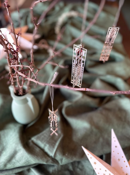 Photo depicting three holiday ornaments hanging from branches. Recommended in the Taliesin 2021 Gift Guide. 